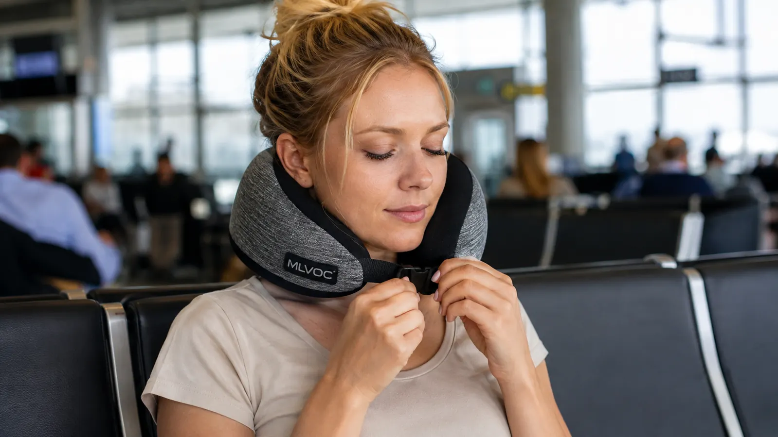 Hand adjusting the chin strap on a memory foam travel neck pillow before boarding